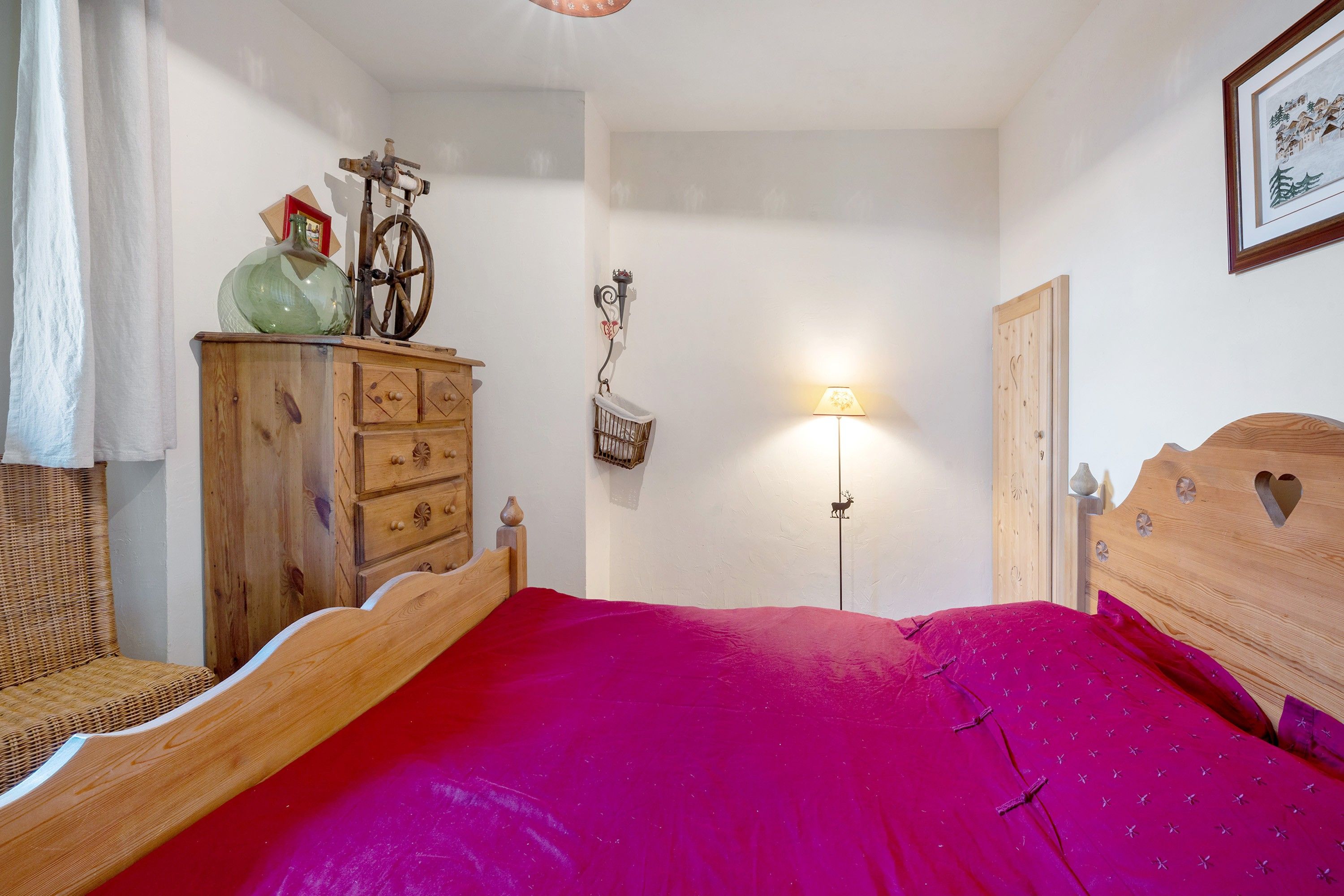Une chambre à coucher avec un lit en bois, une commode, une lampe et une étagère fixée au mur.