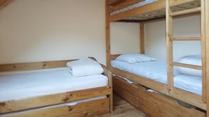 A room with two wooden bunk beds, each with a mattress and pillows.