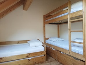 A room with two wooden bunk beds, each with a mattress and pillows.