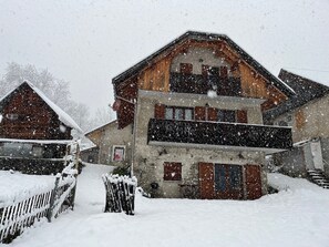 Ett tvåvåningshus byggt av trä, med ett snötäckt tak och ett synligt garage.