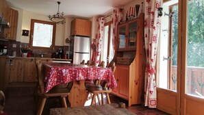 Cozinha acolhedora com armários de madeira, geladeira de aço inoxidável e uma mesa de jantar com cadeiras.