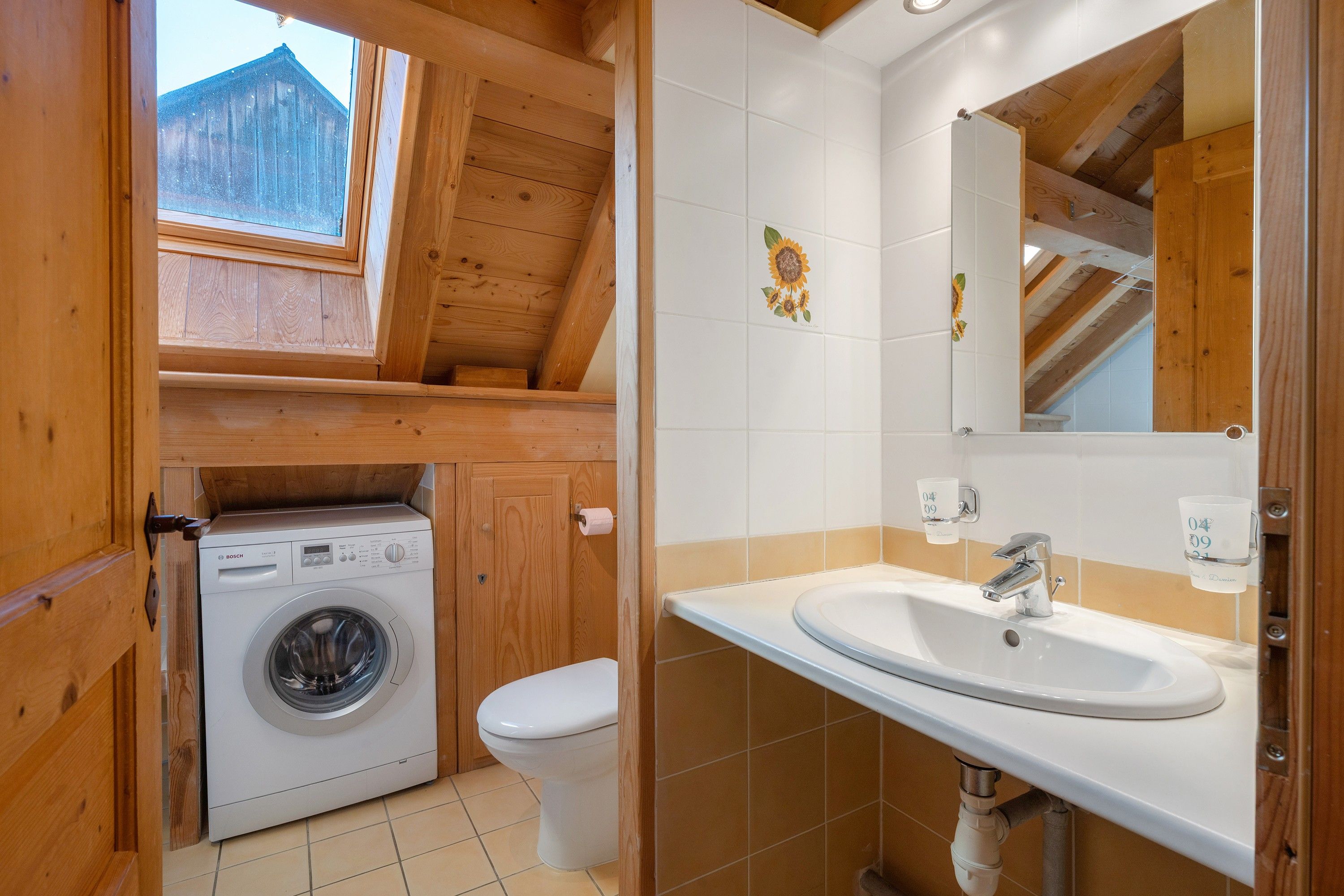 Ein kleines Badezimmer mit Waschmaschine, Toilette und Waschbecken inklusive Spiegel.