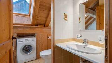 Ein kleines Badezimmer mit Waschmaschine, Toilette und Waschbecken inklusive Spiegel.