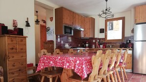 A kitchen with wooden cabinets, a dining table with chairs, a refrigerator, and a microwave.