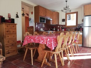A kitchen with wooden cabinets, a dining table with chairs, a refrigerator, and a microwave.