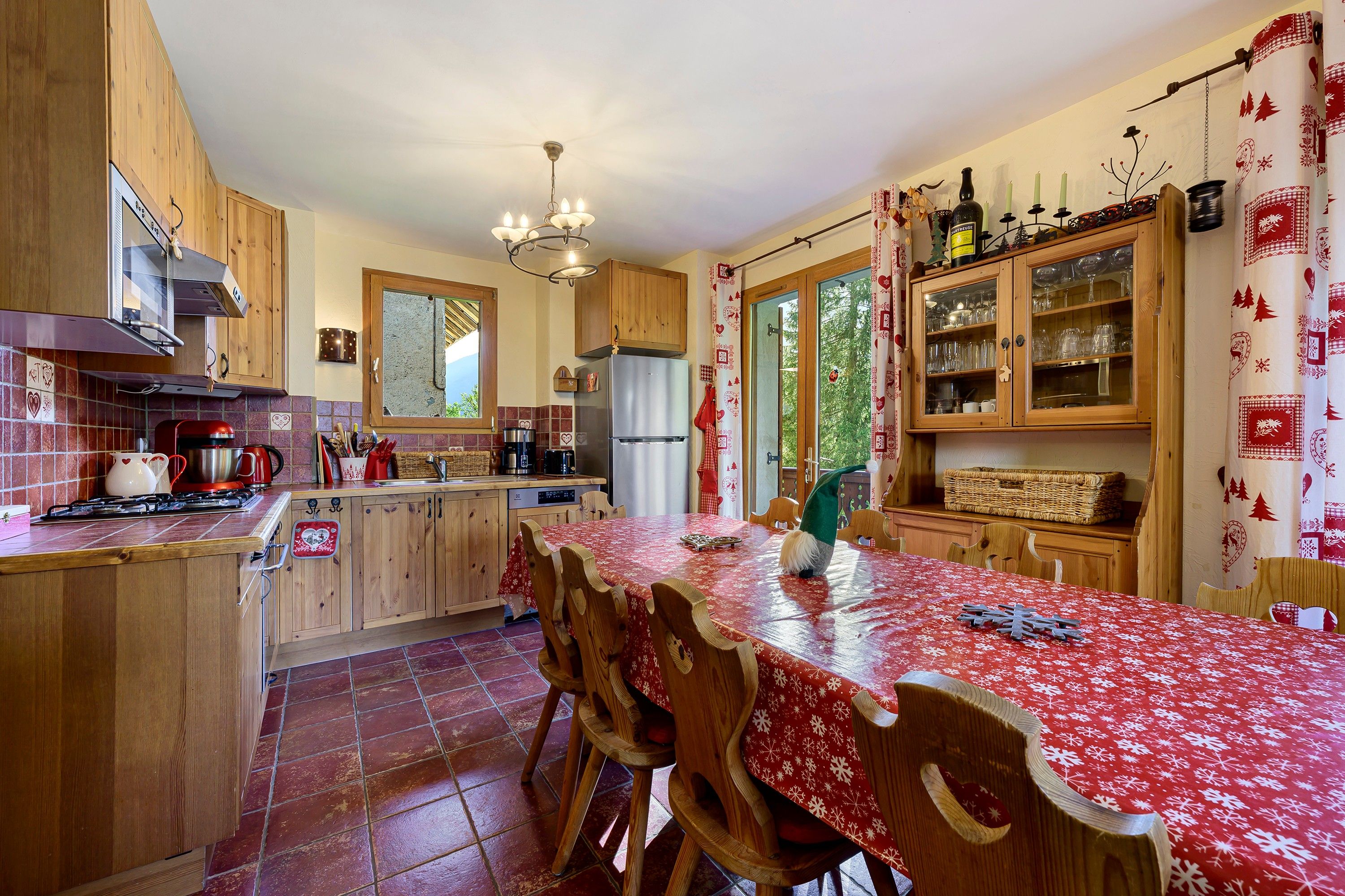 Une cuisine avec des meubles de rangement en bois, un réfrigérateur en acier inoxydable et une table à manger avec des chaises.