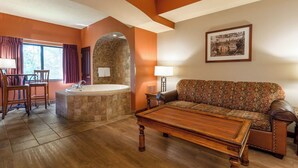 Une pièce avec un plancher en bois, un canapé, une table basse, une baignoire et un coin repas comprenant des chaises et une table.