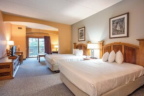 Ett hotellrum med två sängar, ett skrivbord, en stol och en balkong.