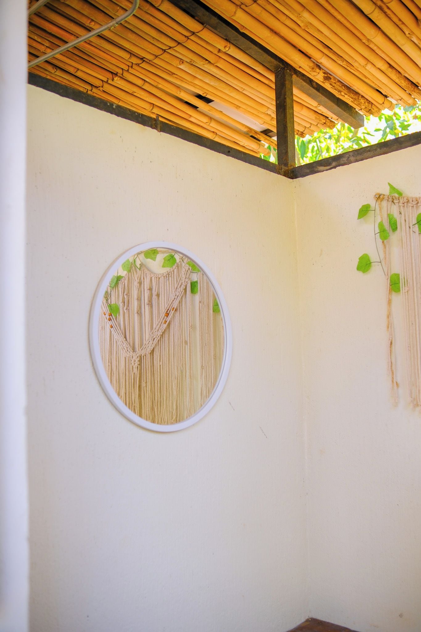 Una habitación con un colgador circular de macramé en la pared y techo de bambú.