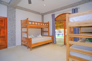 A bunk bed room with a wooden headboard, a door, and a window with curtains. - Las Golondrinas KM-59 (Chiltiupan)