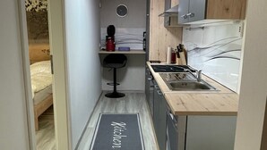 A compact kitchen with a built-in stove, a sink, and a small bar stool.
