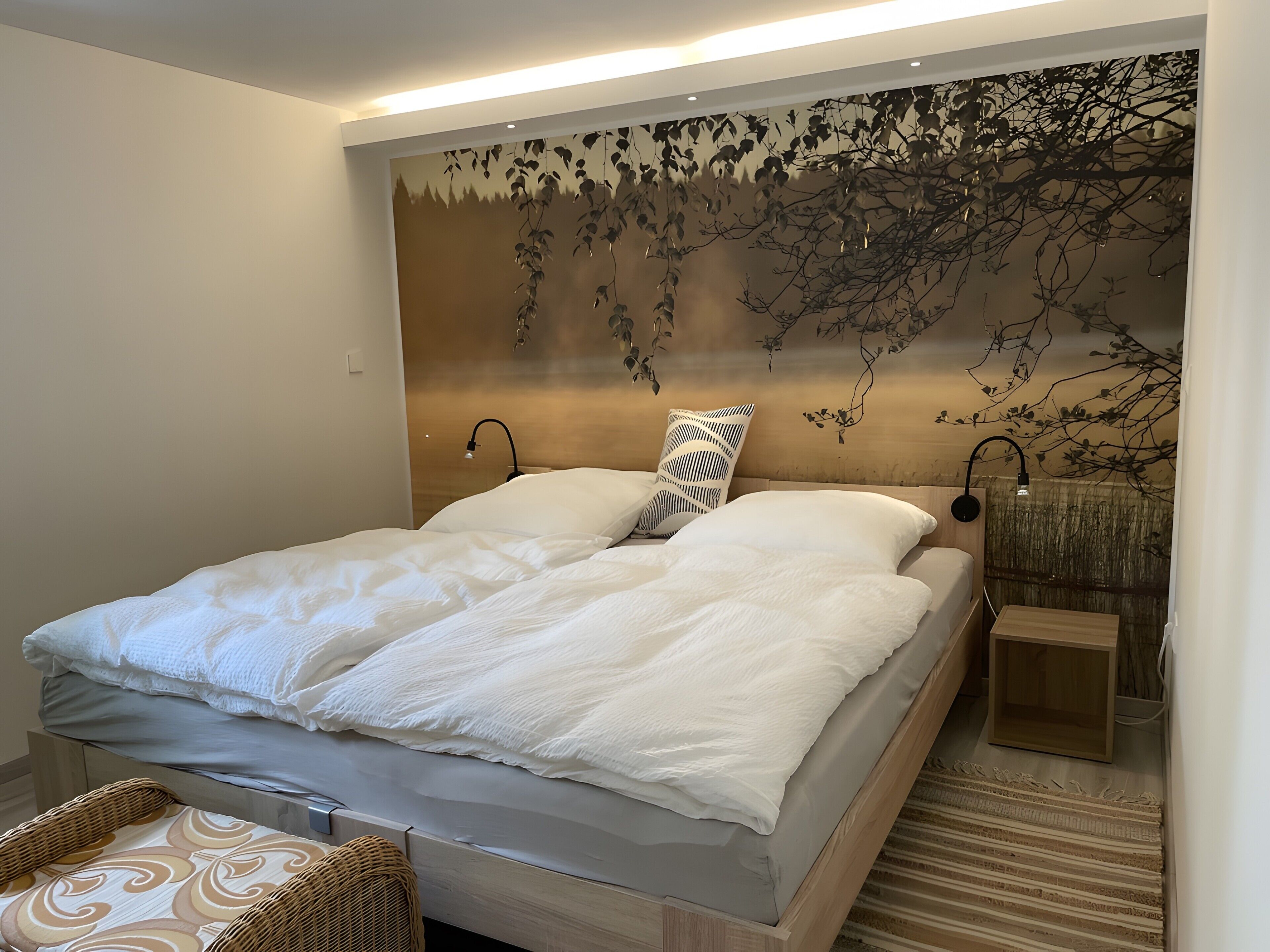 Une chambre à coucher comprenant un lit, des tables de chevet, une lampe fixée au mur et un élément décoratif mural.