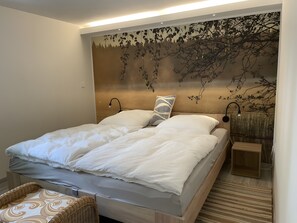 Un dormitori amb un llit, taules de nit, una làmpada penjada a la paret i una decoració mural.