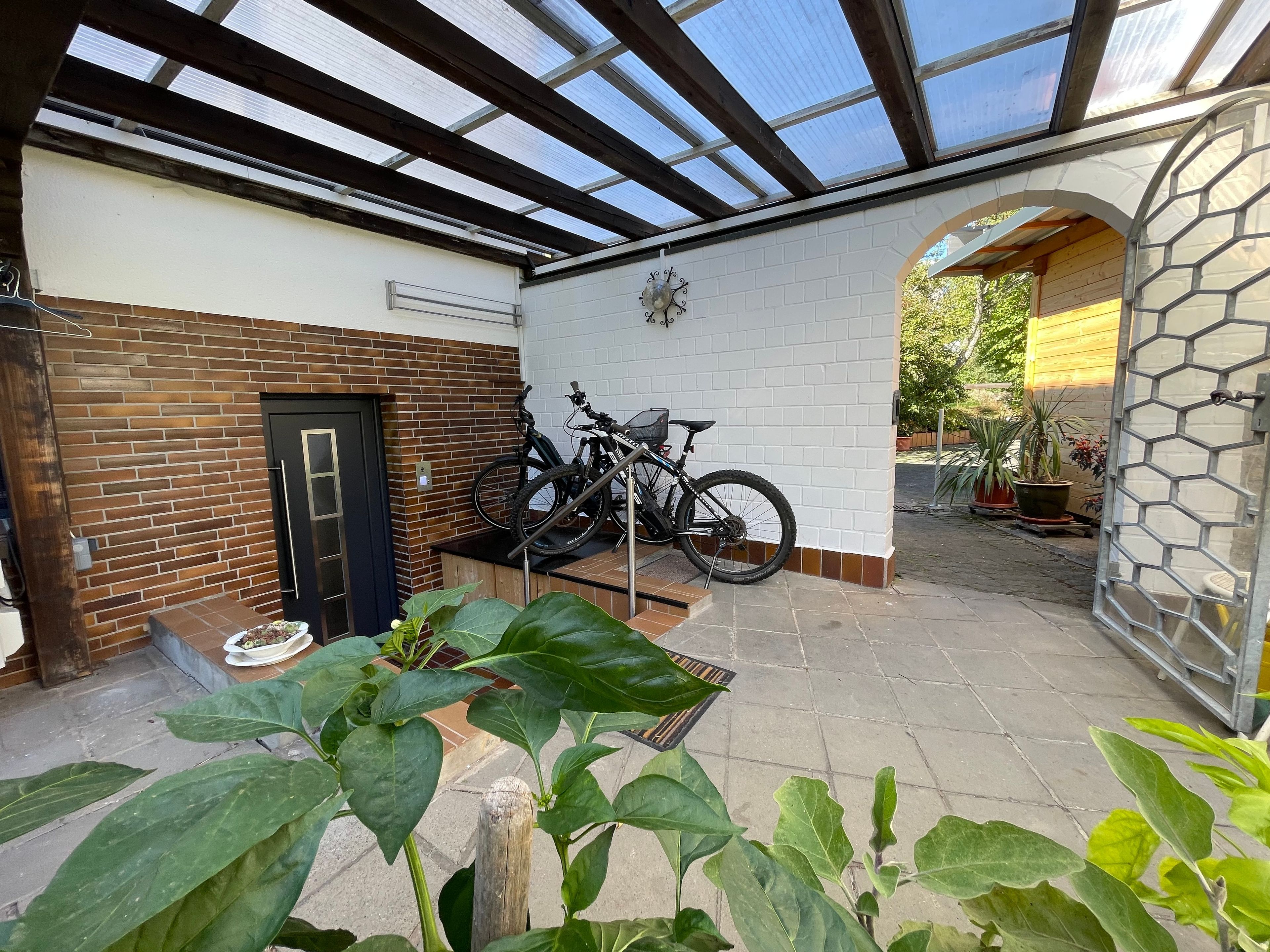 A covered patio area with a brick wall, a door, and a bicycle rack.