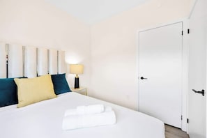 Ein Hotelzimmer mit einem Bett, einem Nachttisch, einer Lampe und einer Tür.