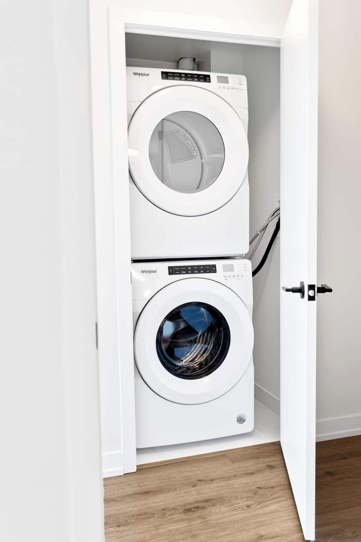 Ein weißer Waschraum mit zwei übereinander gestapelten Whirlpool-Waschmaschinen.