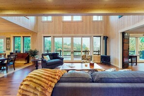 A spacious living area with a large window, a fireplace, and a cozy seating arrangement. - 3BR waterfront home with dock and hot tub (Bainbridge Island)