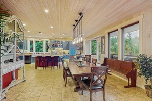 A spacious kitchen with a dining area, wooden ceiling, and large windows. - 3BR waterfront home with dock and hot tub (Bainbridge Island)