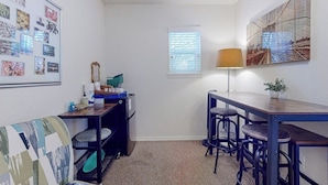 Una habitación compacta con kitchenette, un pequeño comedor y una pared decorada con cuadros.
