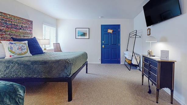 Un dormitorio con cama, escritorio, televisión y puerta.
