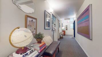 A hallway with a globe, books, a bench, and framed artwork on the walls.