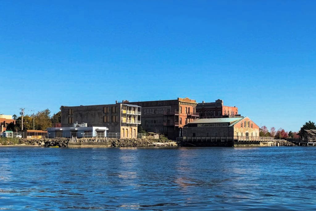 A waterfront building with multiple levels, a dock, and a clear blue sky.