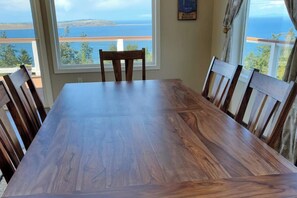 A dining table with chairs, a window with a view of the sea, and a framed picture on the wall. - Fantastic 3BR Oceanview with decks, gas grill (Sequim)
