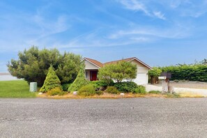 A two-story house with a red door, surrounded by well-maintained greenery and a gravel driveway. - Fantastic 3BR Oceanview with decks, gas grill (Sequim)