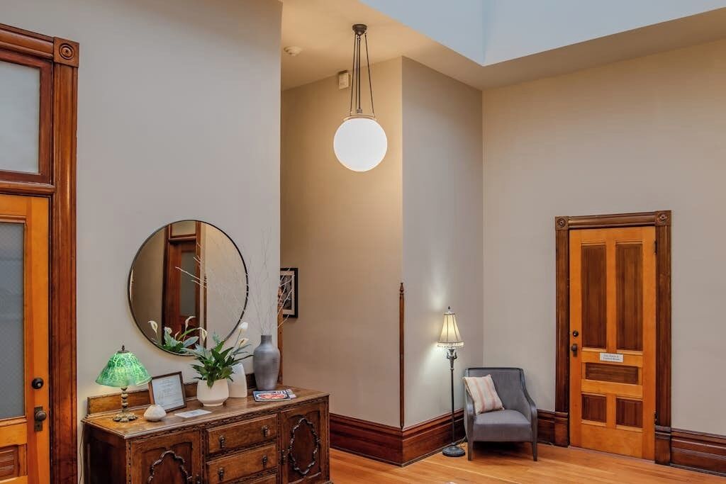 A room with a wooden dresser, a mirror, a lamp, and a door.