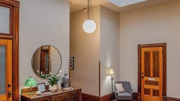 A room with a wooden dresser, a mirror, a lamp, and a door.