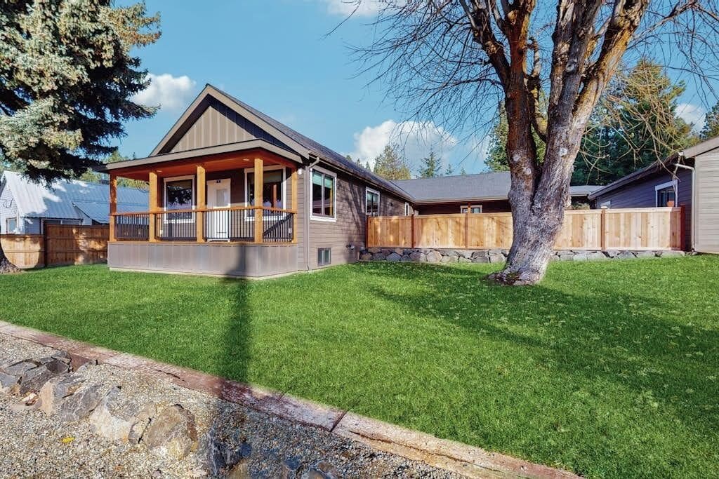 Ein Wohnhaus mit umzäuntem Garten, einer Holzdar Terrasse und einer Steinmauer.