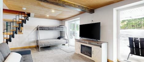 Una habitación con literas, televisión, sofá y chimenea.