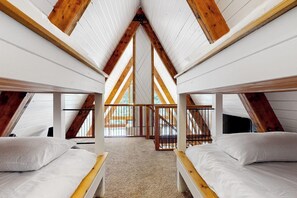 An attic bedroom with wooden beams, two beds, and a view of the outside. - Modern A-frame 2BR near lake & lifts with firepit (Snoqualmie Pass)