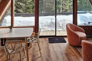 Ein modernes Interieur mit Holzboden, einem weißen Tisch und einer Sitzecke mit gepolstertem Sessel.