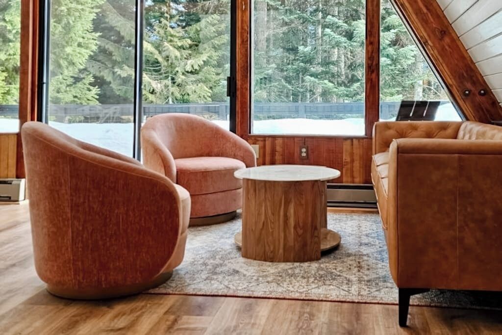 Un salon moderne avec une grande fenêtre, une table basse ronde en bois et deux canapés.
