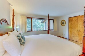 Une chambre à coucher avec un grand lit, une fenêtre avec des rideaux, une armoire en bois et un tableau accroché au mur.