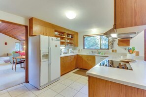 Une cuisine moderne avec des meubles en bois, un réfrigérateur encastré et une fenêtre qui laisse entrer la lumière naturelle.