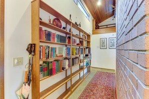 Un couloir avec une bibliothèque en bois remplie de livres, un tapis à motifs et un mur en briques.