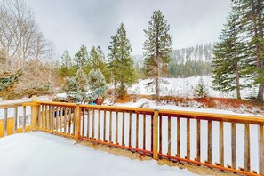 A wooden deck with a railing overlooking a snowy landscape with trees. - 2BR cabin with balcony, grill, & Washer Dryer (Cle Elum)