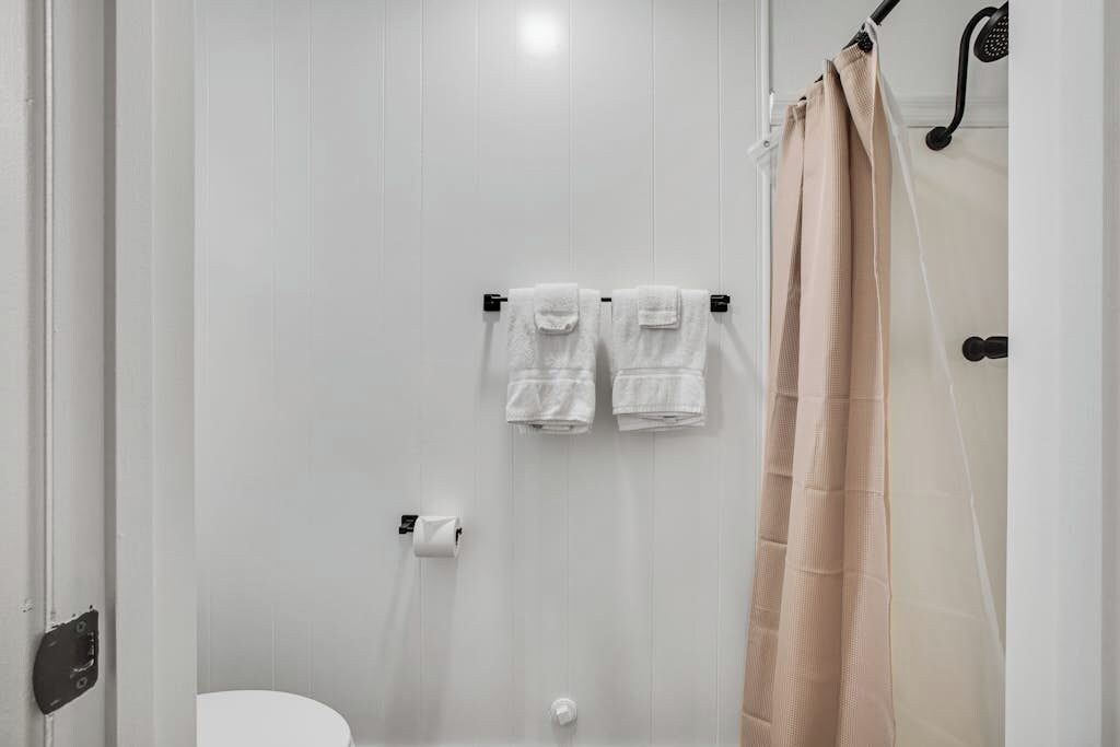 Une salle de bain avec des toilettes, deux serviettes suspendues à un porte-serviettes et un rideau de douche.