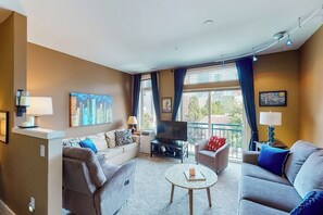 Un salon moderne avec un canapé, une table basse et un téléviseur à écran plat.