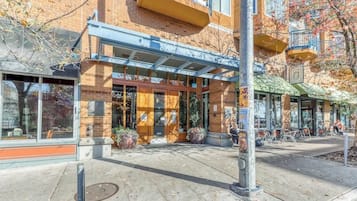 Un bâtiment à la façade en briques, doté de grandes fenêtres et d’un espace extérieur aménagé pour s’asseoir.