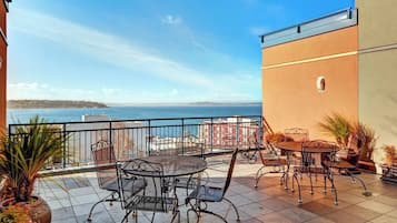 Une terrasse avec mobilier d’extérieur, une vue sur la mer et un bâtiment doté d’un balcon.