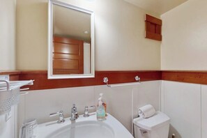 Une salle de bain équipée d’un lavabo, d’un miroir, d’un porte-serviettes et de toilettes.
