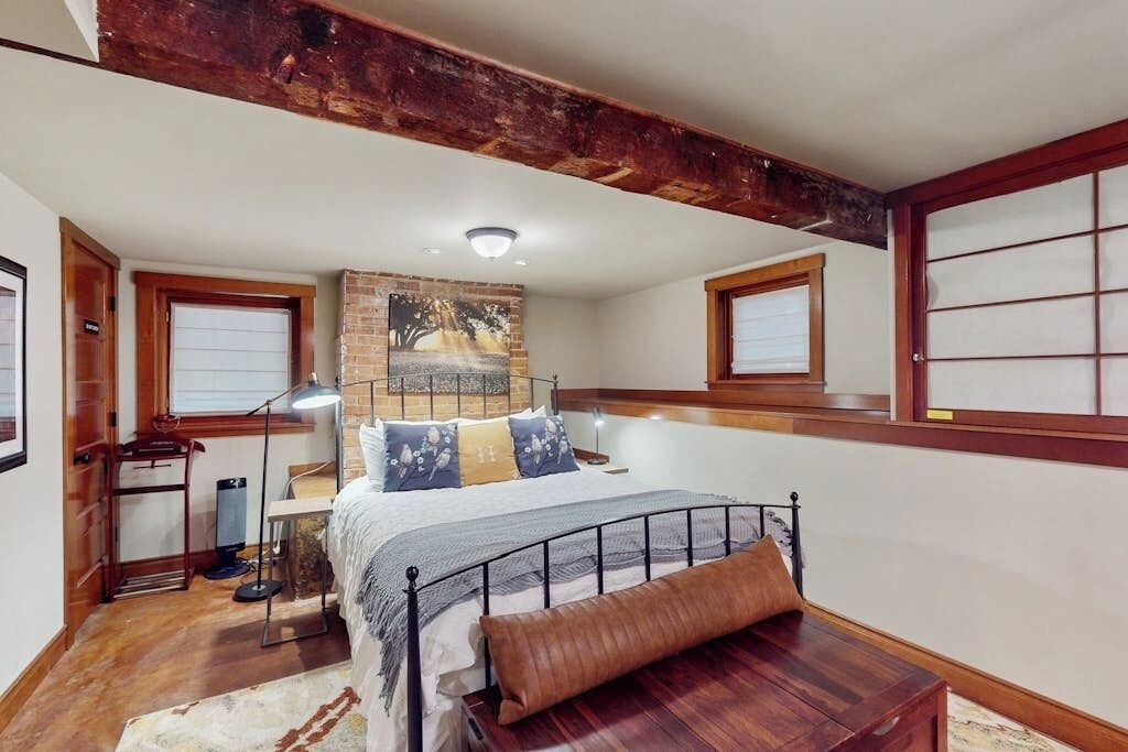 A bedroom with a bed, a desk, a lamp, and a window.