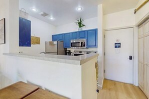 A kitchen with blue cabinets, a stainless steel microwave, and a refrigerator. - Dog-Friendly Condo with Heated Pool, Hot Tub, Balcon (Seattle)