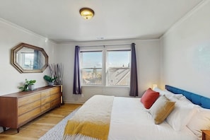 A bedroom with a bed, a dresser, a mirror, and a window with curtains. - 2 BR Home in the heart of Beacon Hill (Seattle)