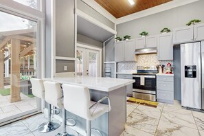 A modern kitchen with a central island, bar stools, and stainless steel appliances.