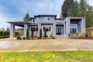 A modern two-story house with a stone facade, multiple windows, and a well-maintained front yard.