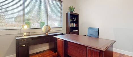 A room with a large wooden desk, a bookshelf, a globe, and a chair.